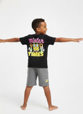 Child wearing a black t-shirt with colorful text and graphics, standing against a white background