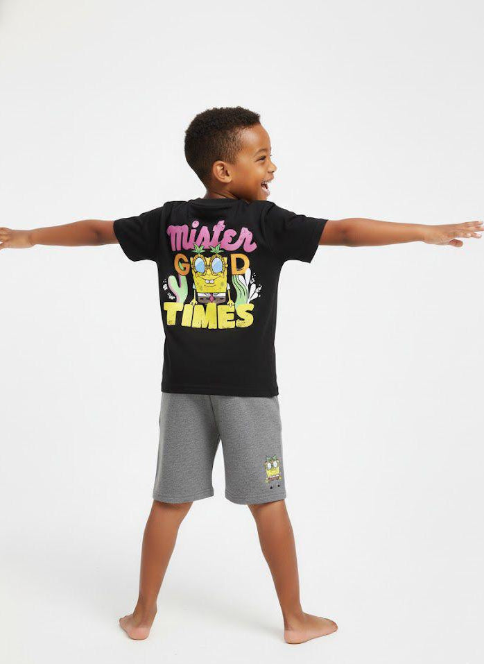 Child wearing a black t-shirt with colorful text and graphics, standing against a white background